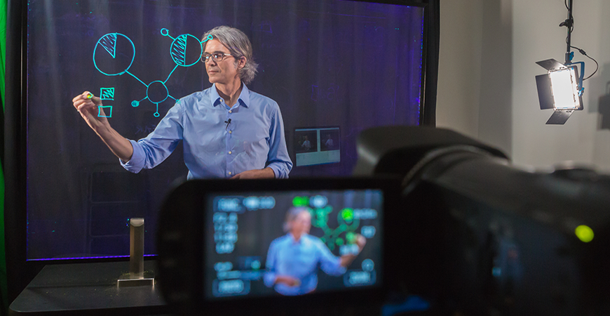 A teacher recording a video lecture at a learning glass screen.