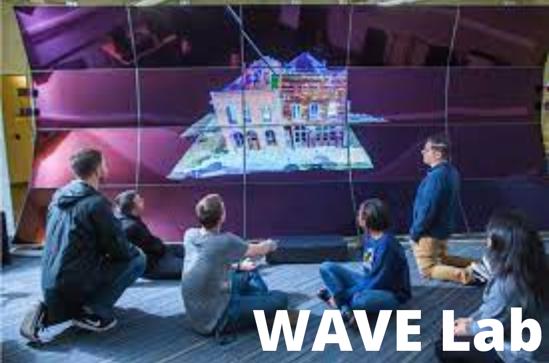 Group of people sitting down looking at an image of a house on giant purple screen with the caption "WAVE Lab"