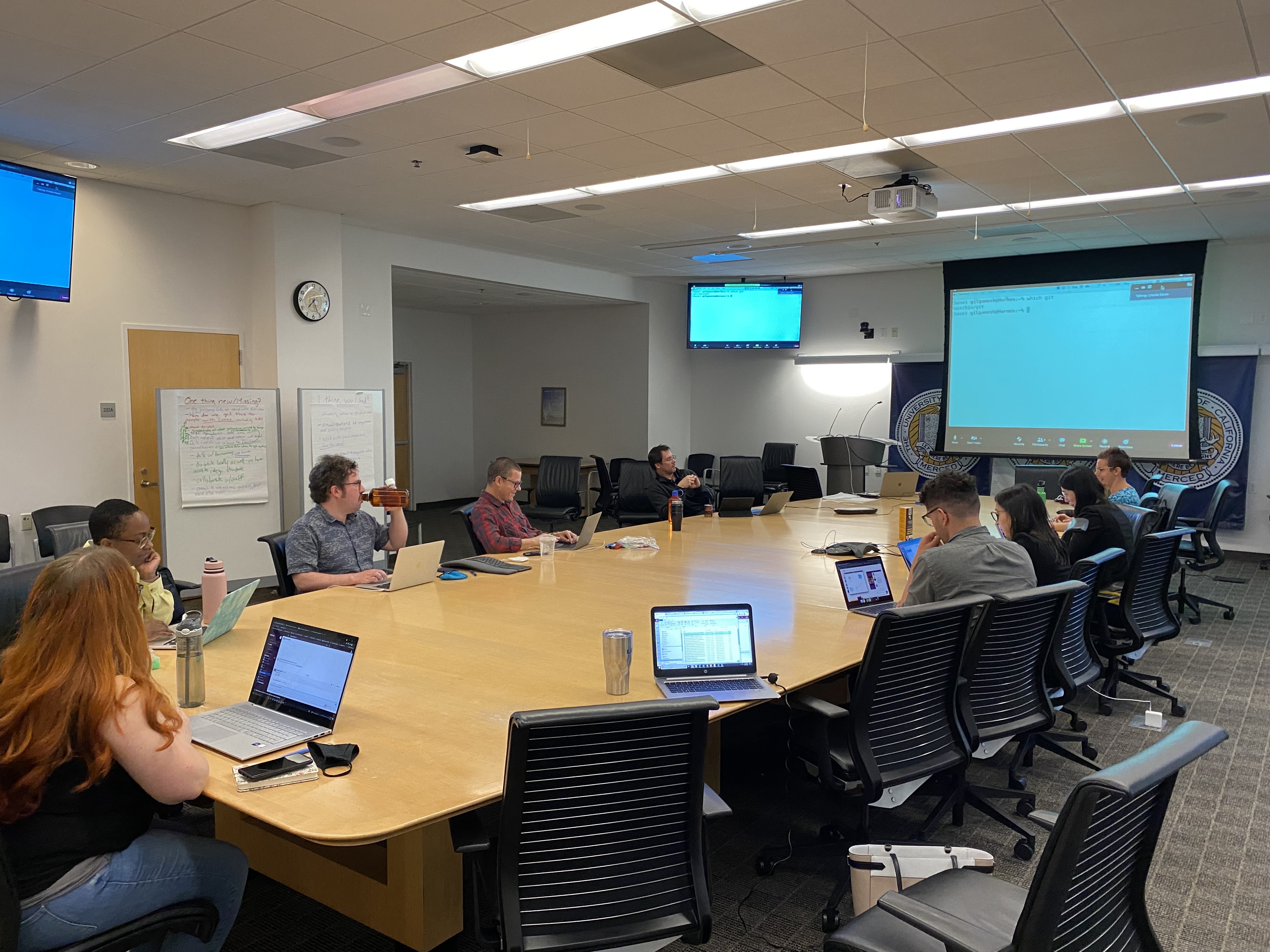 People in a meeting with computer screens as they are in a conference room