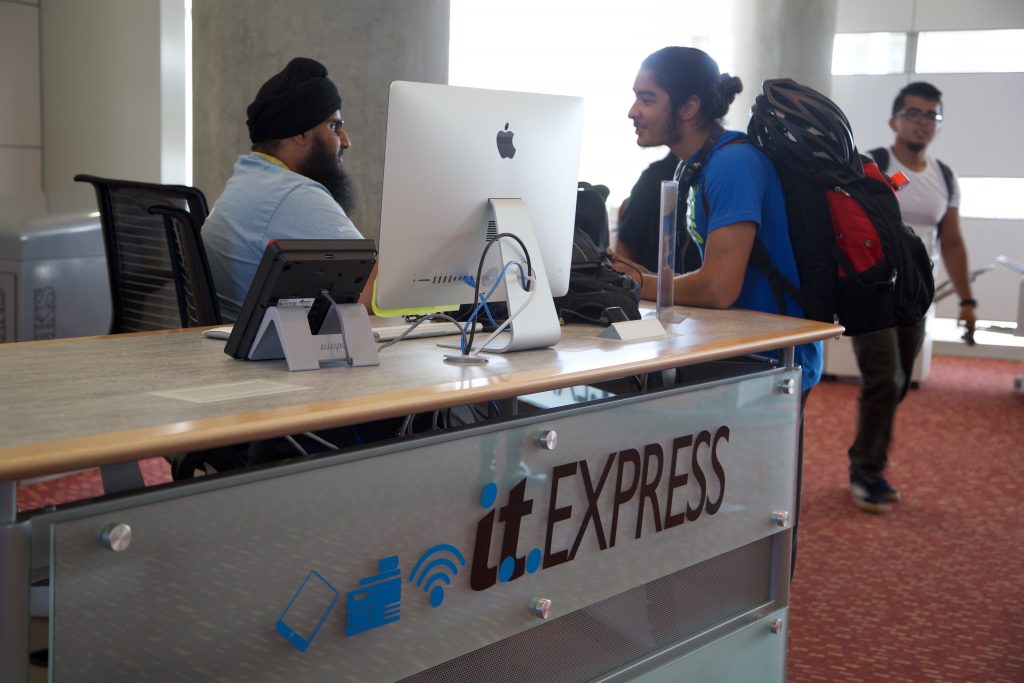 OIT worker helping student at the Library Service Desk